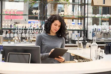 coffee shop owner behind counter looking at tablet