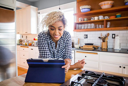 Woman in kitchen looking at digital tablet