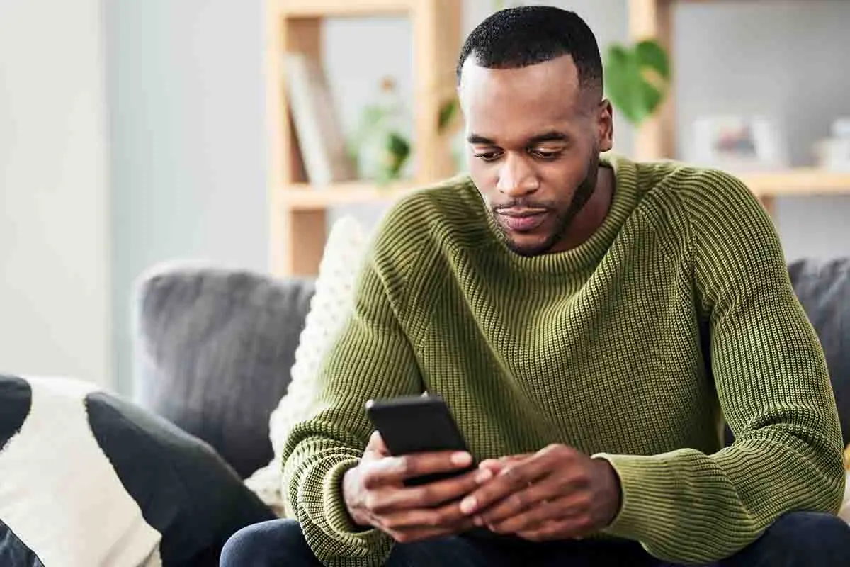 man looking at phone while sitting on sofa