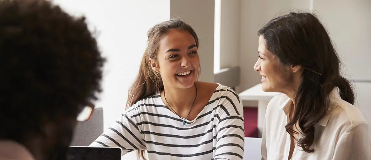a woman in a striped shirt talking with another woman