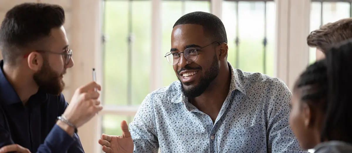 a man wearing glasses, talking to two other people