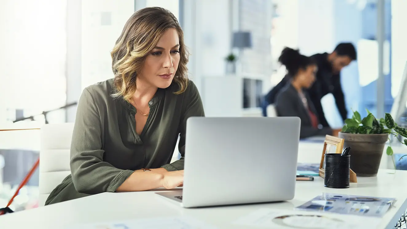 Office woman on laptop at desk looking at options to upgrade b2b payment acceptance methods.