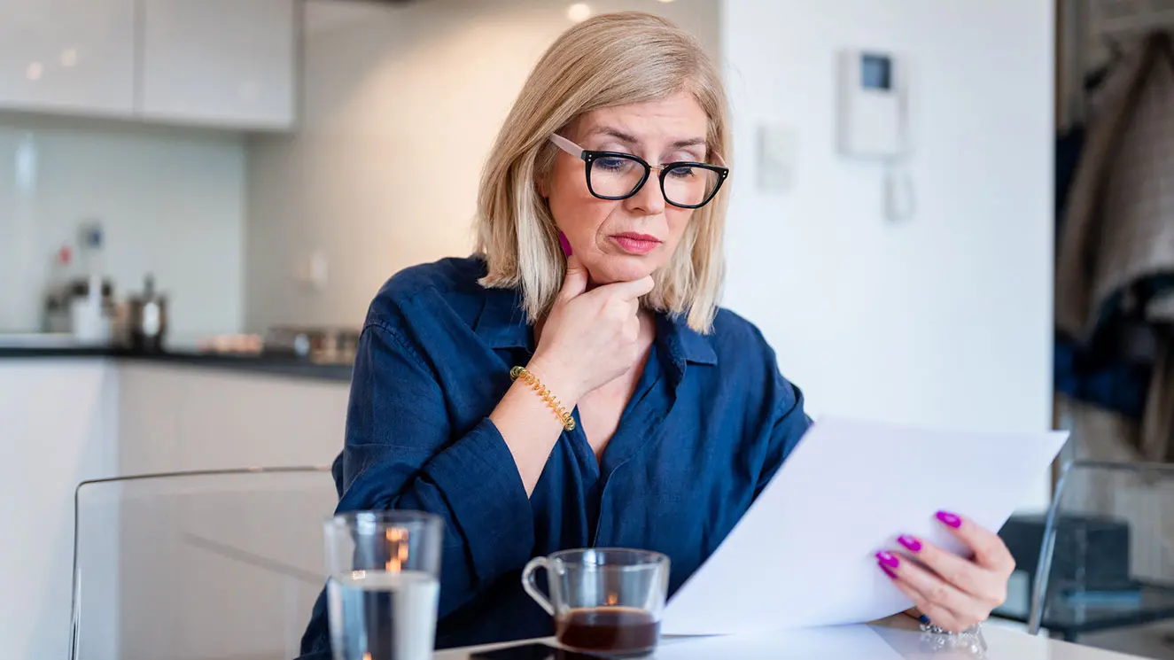 A woman looking at paperwork in her kitchen
