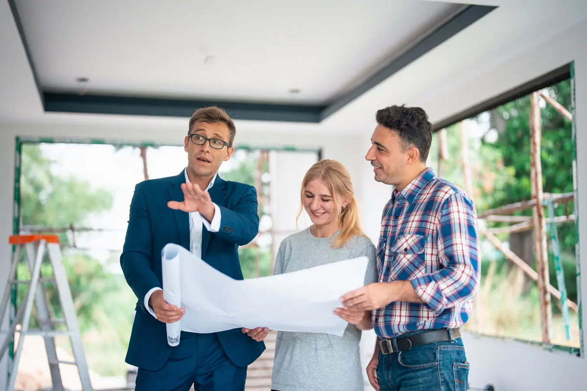 a man and woman looking at blueprints with their architect