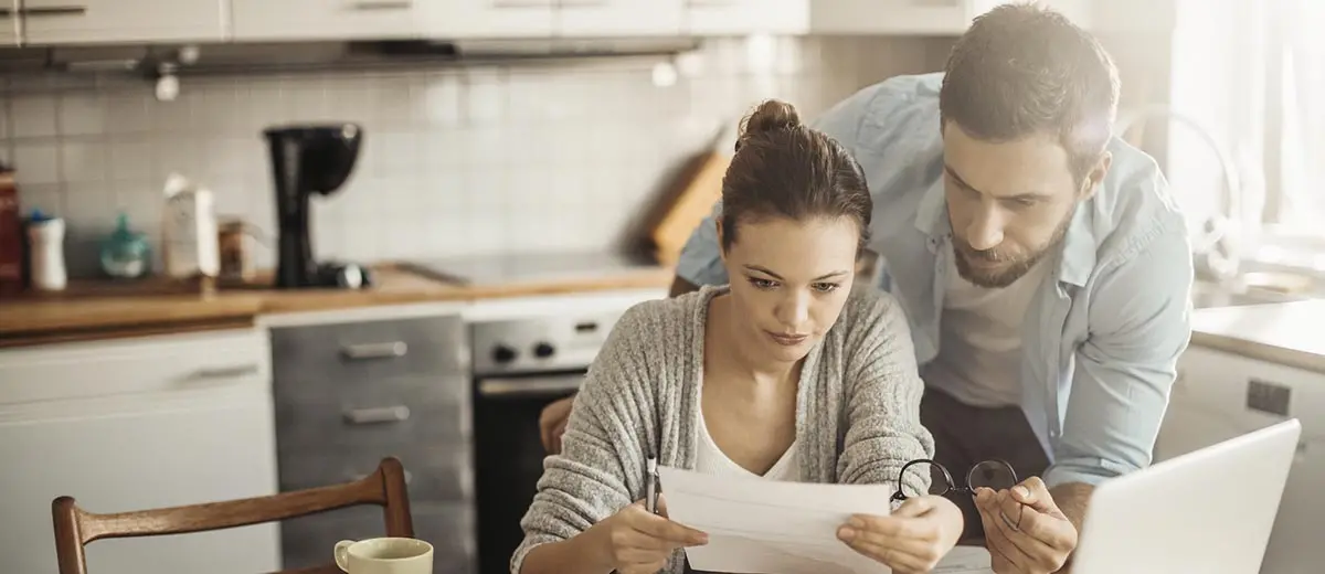 a man and woman looking at a computer in their kitchen
