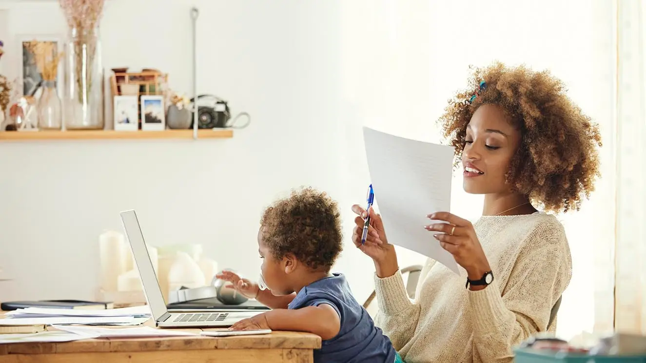 mother looking at bills with a child in her lap