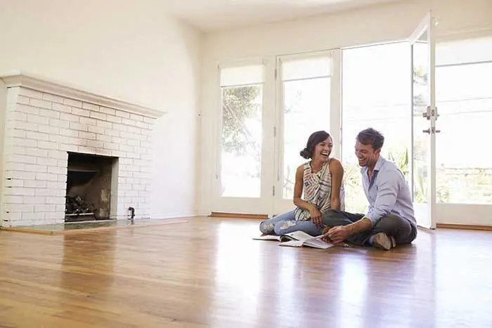a man and a woman sitting on the floor of an empty living room