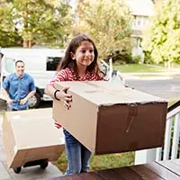 a young girl carrying a moving box