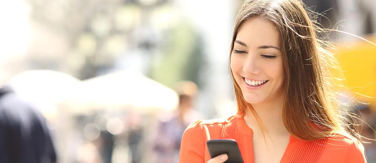 woman in an orange shirt looking at her mobile phone