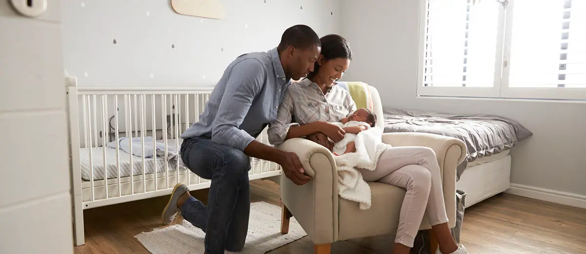 man and woman in a nursery holding a newborn