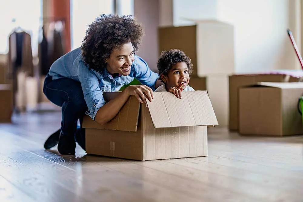 a woman smiling at a child who is sitting inside of a moving box