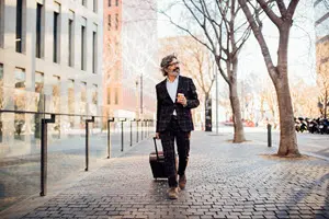 a man pulling his suitcase down a sidewalk