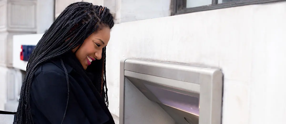 woman in a black coat using an outdoor ATM