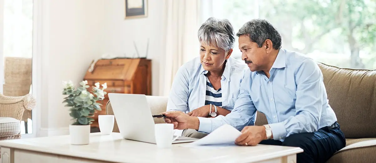 two people looking at paperwork on their couch