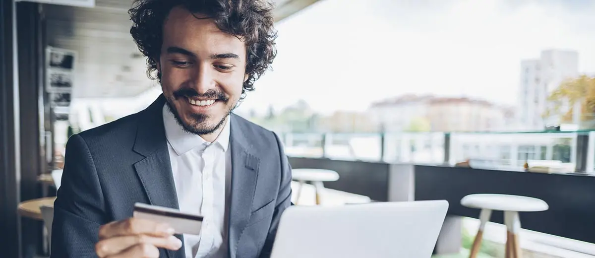 man in a grey blazer looking at a credit card