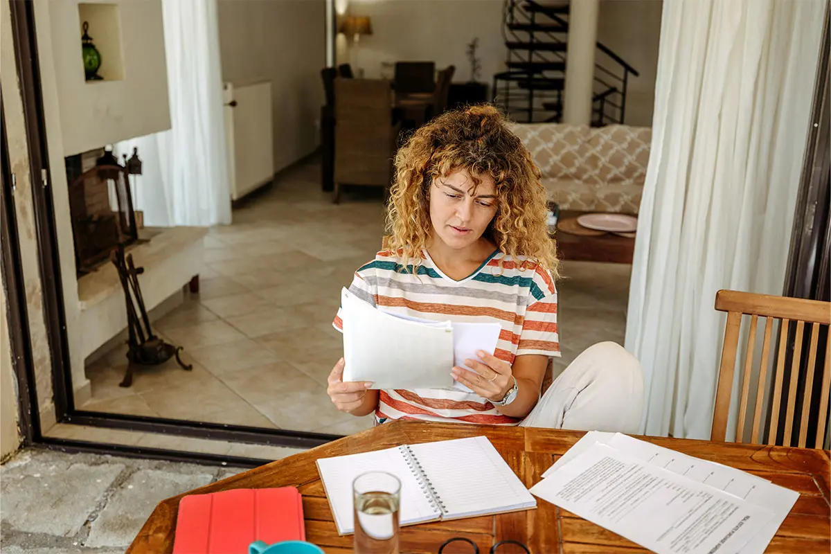 woman in a striped shirt working on a budget at her kitchen table