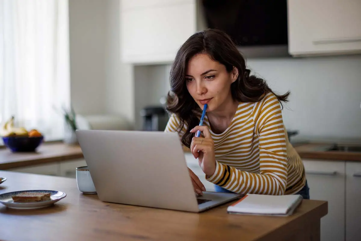 woman working on computer while standing at kitchen counter
