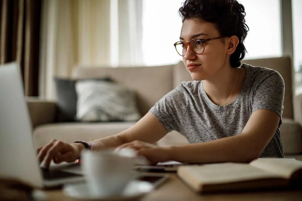 A woman focused on her laptop, using a mortgage calculator to crunch numbers 