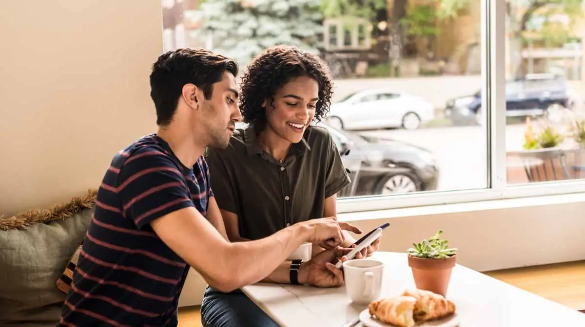 couple in cafe looking at phone together