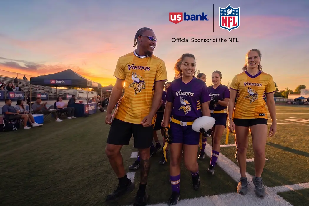Vikings player Justin Jefferson smiling and laughing on the football field with several children.