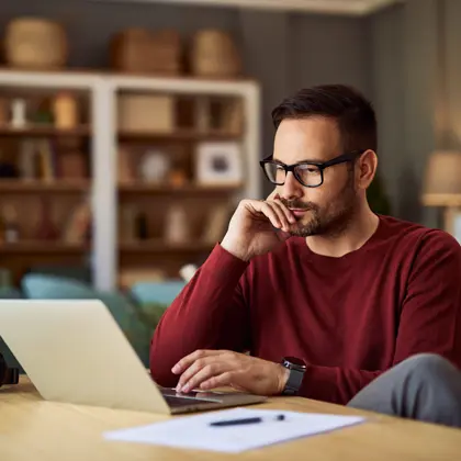 Man with glasses looking at a laptop screen
