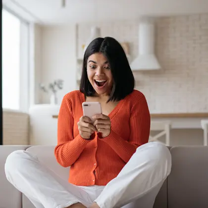 Woman looking excitedly at her phone.