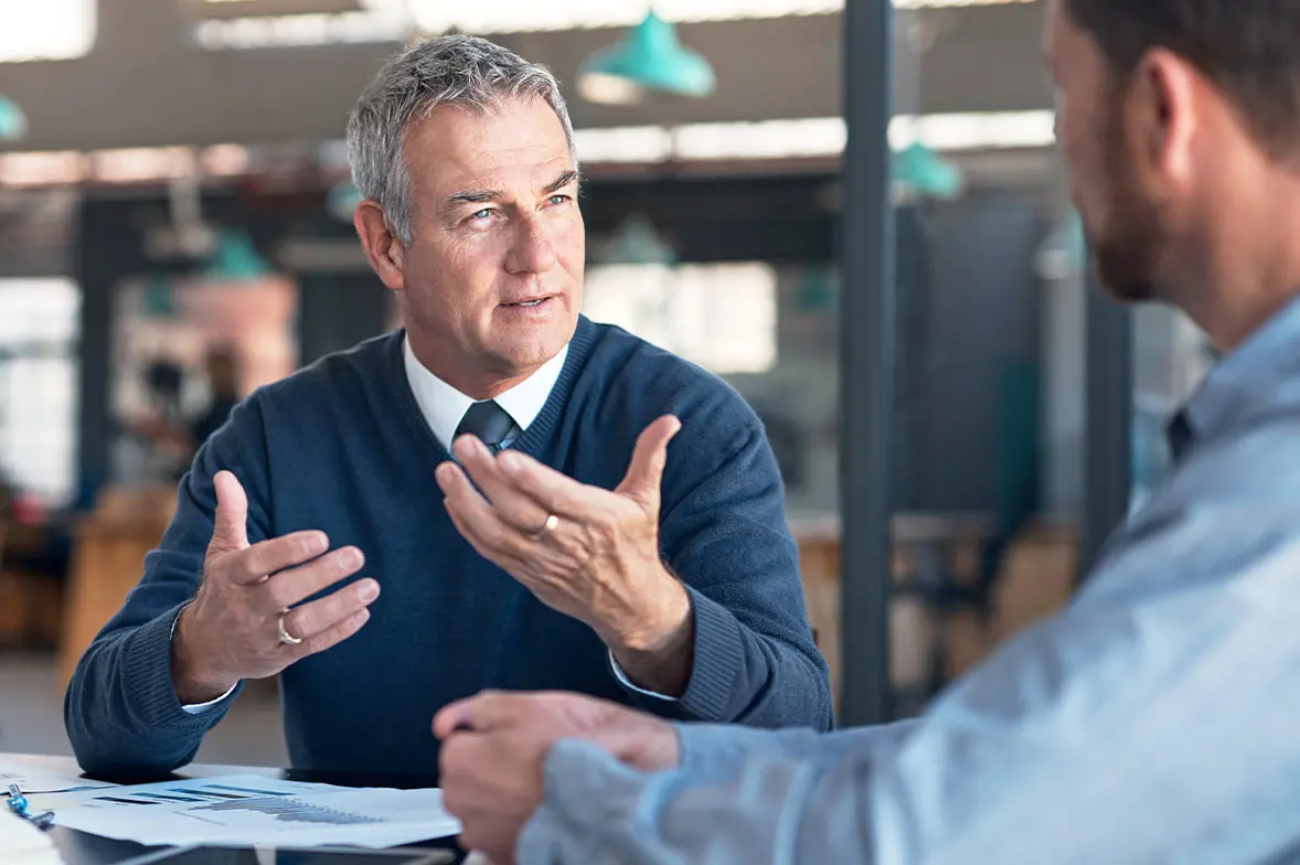 Man wearing a sweater talking to an investment manager