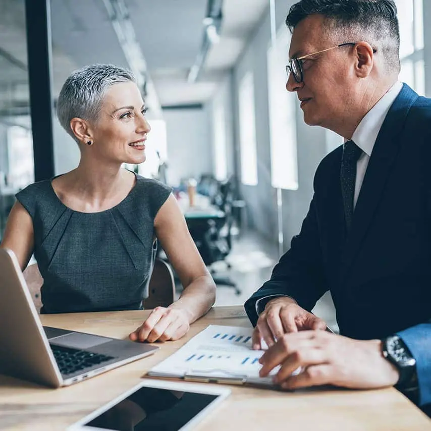 Two coworkers, a man and woman, discussing RIA business in their office 