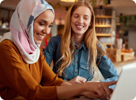 Two students collaborating at a part-time job on completing a task with a laptop
