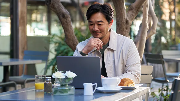 Man sitting in an outdoor café using a laptop