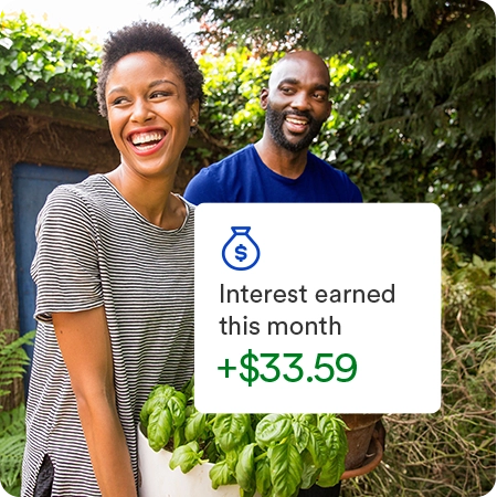 Happy couple carrying plants in a backyard garden with overlay displaying interest earned this month of 33.59 dollars. 
