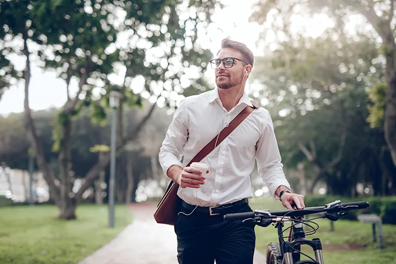 Man walking with his bike holding a coffee