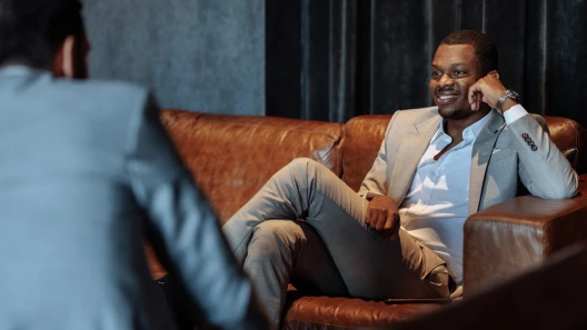 Businessman sitting on a leather couch talking with his financial planner
