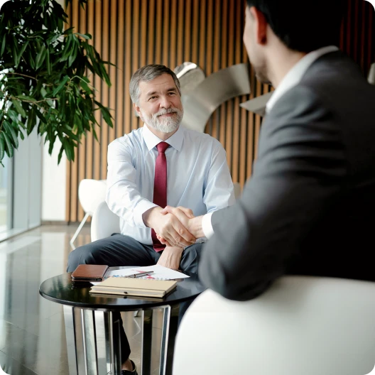 Two middle aged men shaking hands in a meeting 