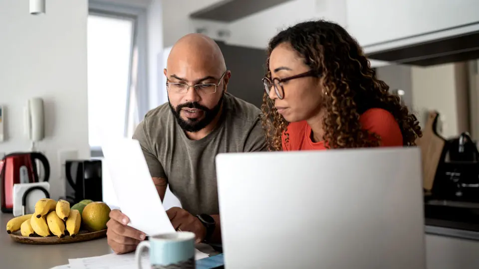 couple in kitchen reviewing investment documents and on the computer
