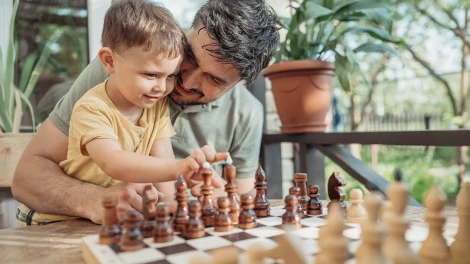 Father teaching his young son how to play chess