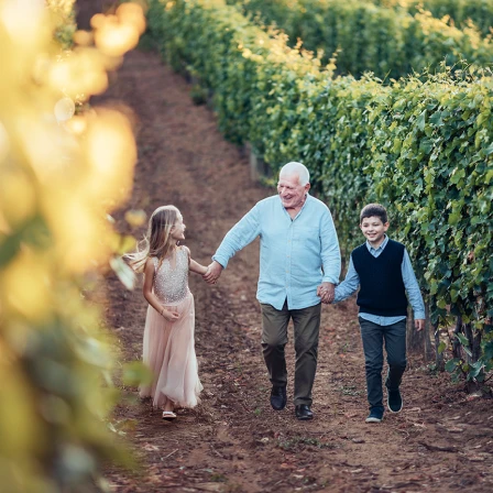 Grandpa walking with grandkisd in a vinyard