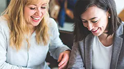 Two women smiling and laughing during conversation