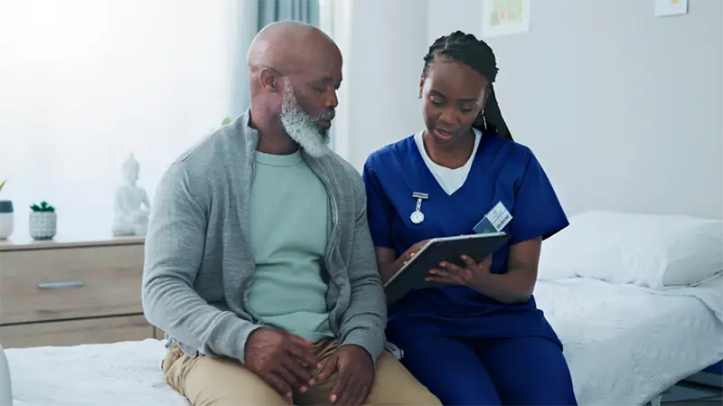 Doctor and patient sitting on a hospital bed talking