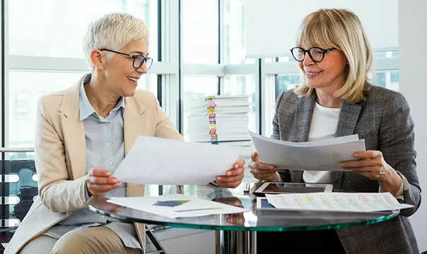 Two business women share paperwork in an office