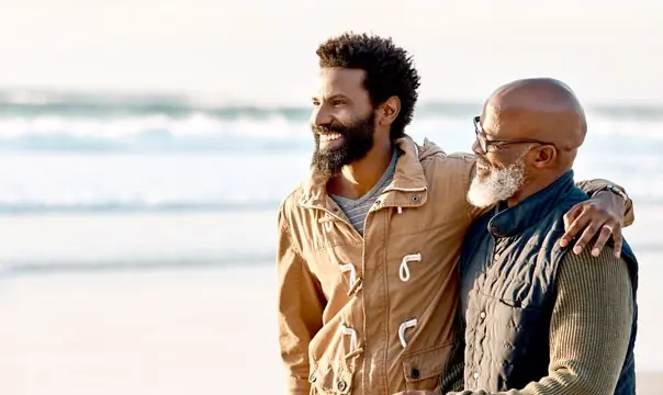 father and son with arms around each other at the beach