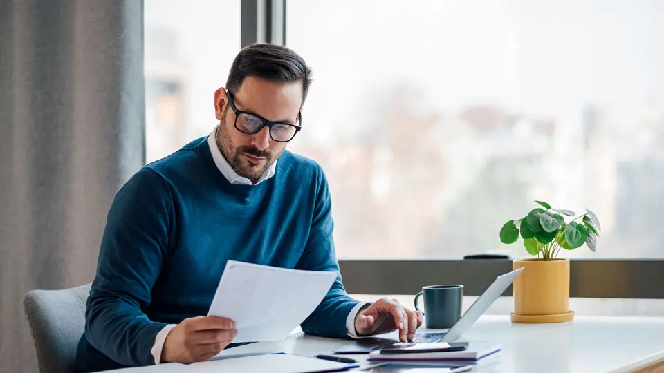 man reviewing paperwork at table