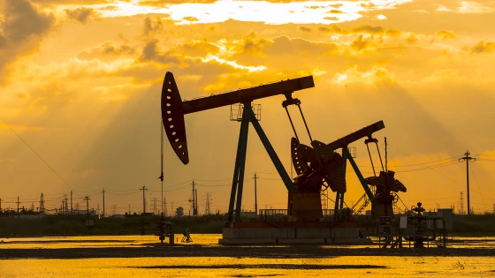 Oil pump jacks silhouetted against sunset sky