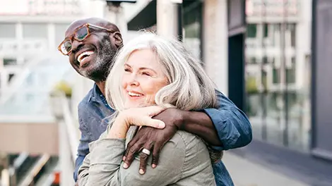 Older couple stand next to each other smiling and looking upward