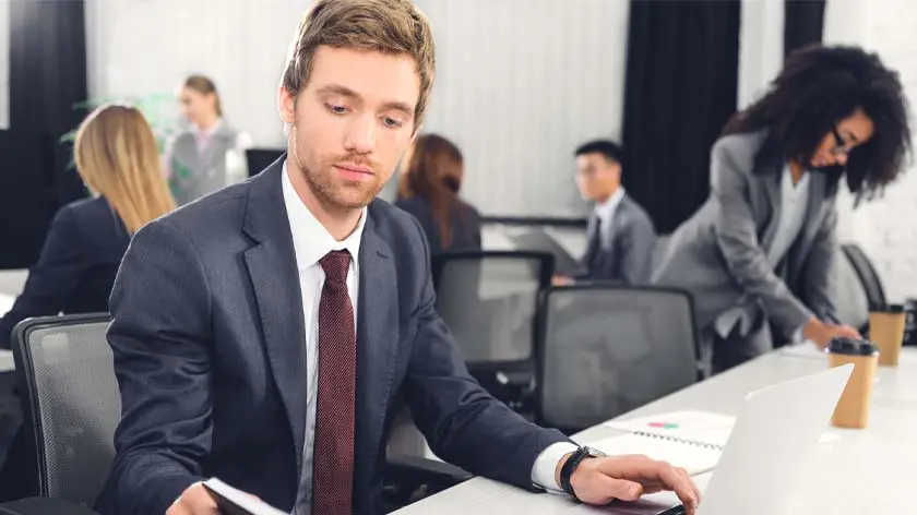 Man wearing a suit using a laptop to make cross-border payments.