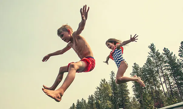 Two kids jumping into a lake