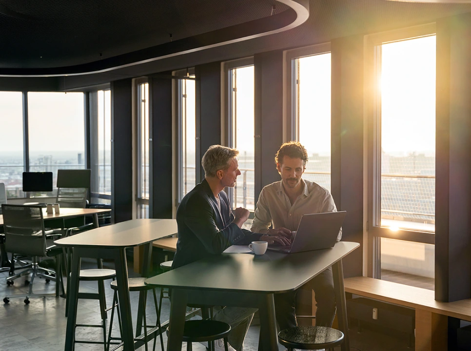 two people looking at laptop at sundown