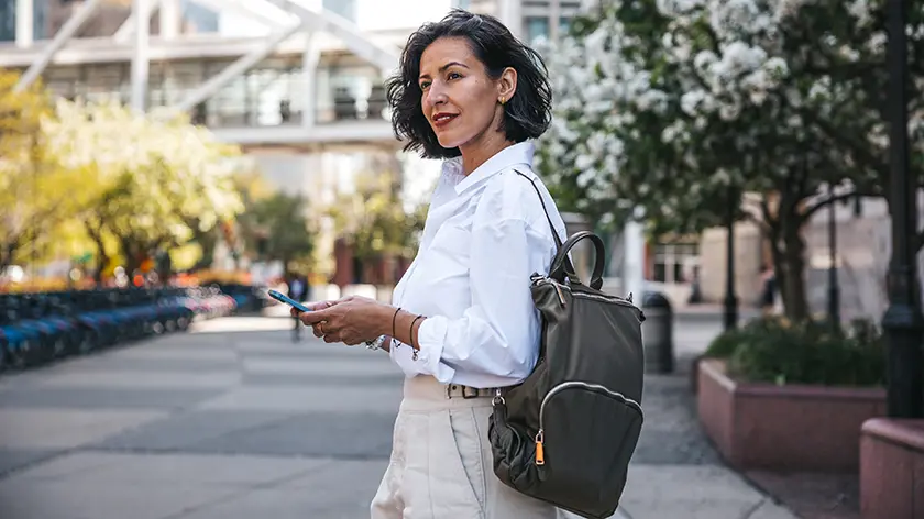 Business woman on city sidewalk holding phone