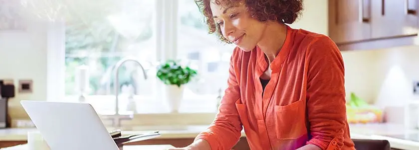woman sitting in her kitchen working on her computer