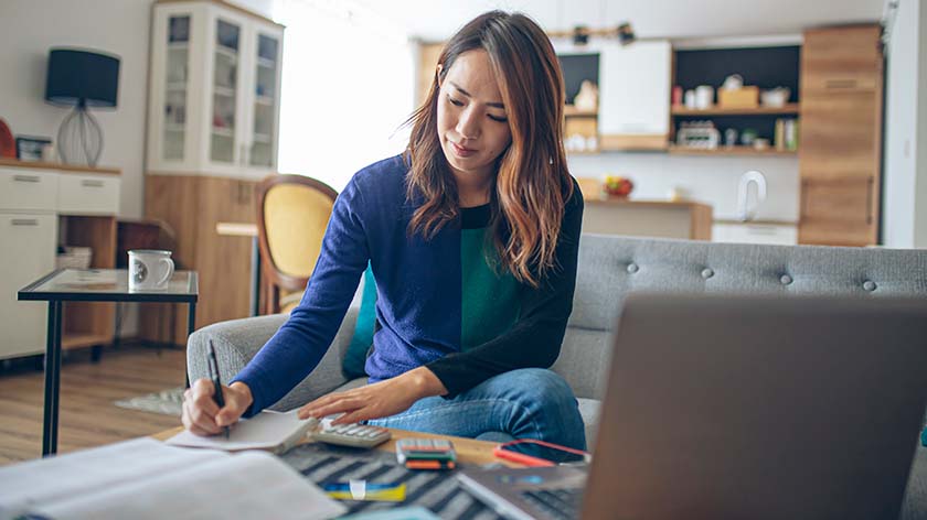 A young woman sitting on her couch managing her finances